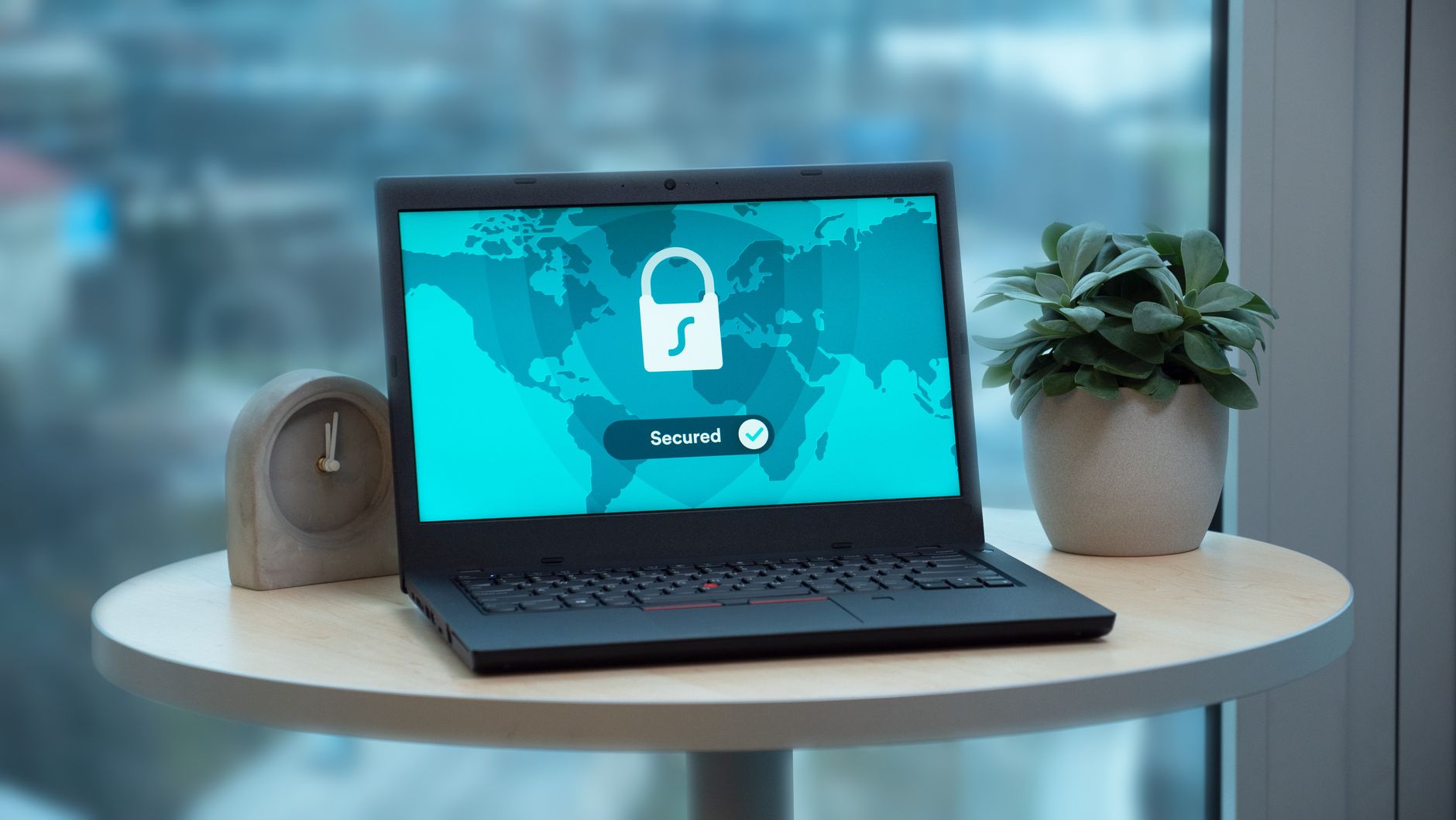 ordinateur portable affichant un cadenas et la mention sécurisé, posé sur une table ronde près d'une fenêtre