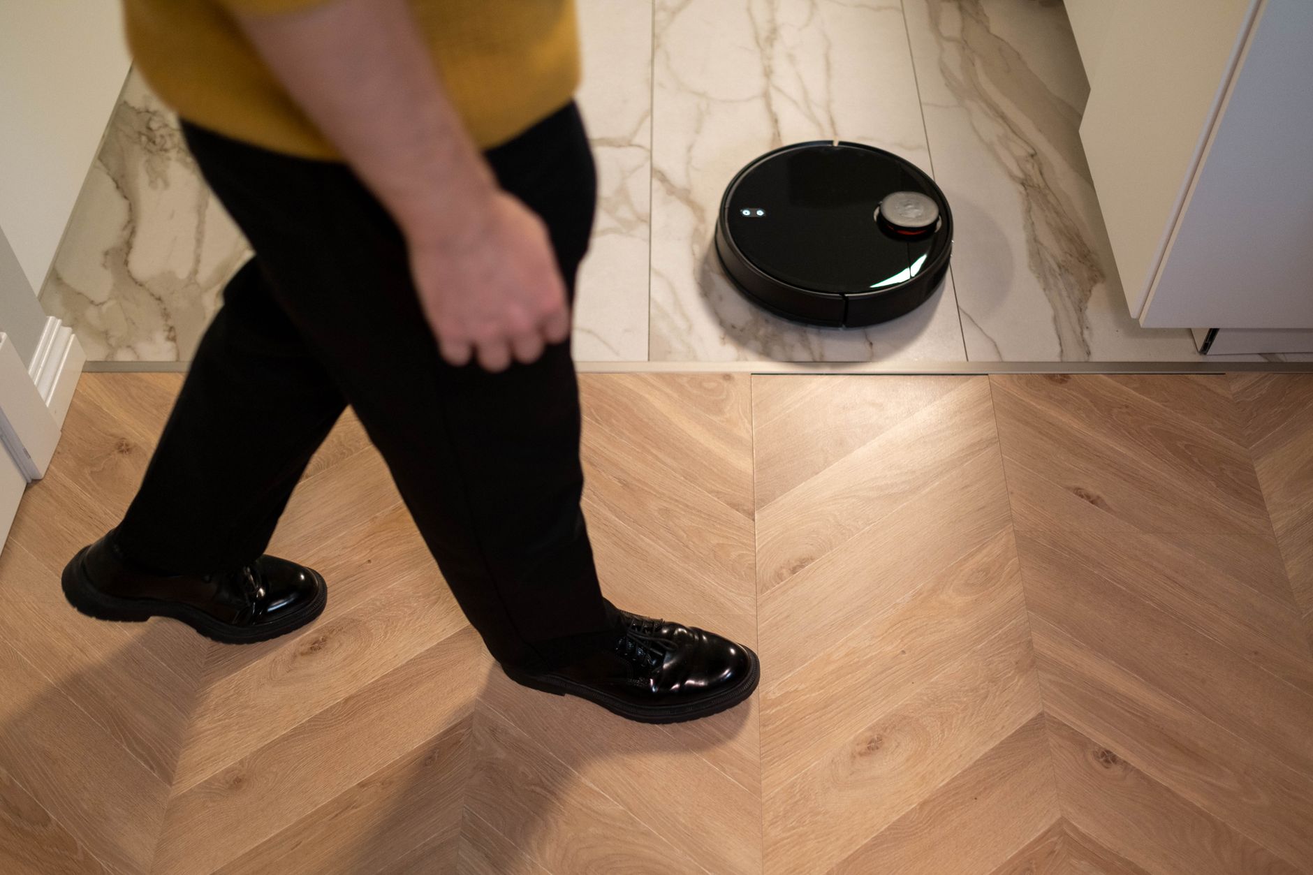 robot laveur autonome qui nettoie un sol carrelé pendant qu'une personne marche à proximité