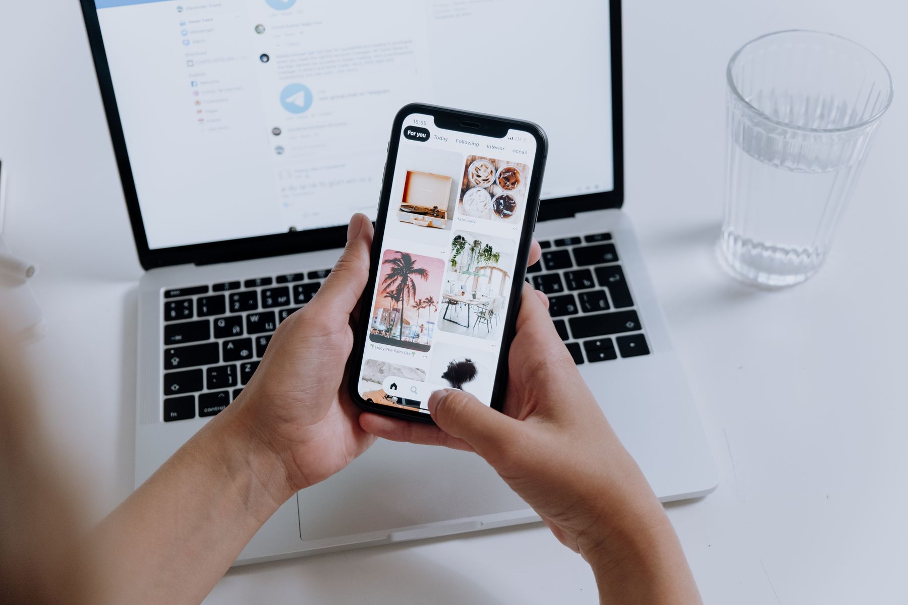 mains tenant un smartphone qui affiche une boutique en ligne, un ordinateur portable ouvert en arrière-plan